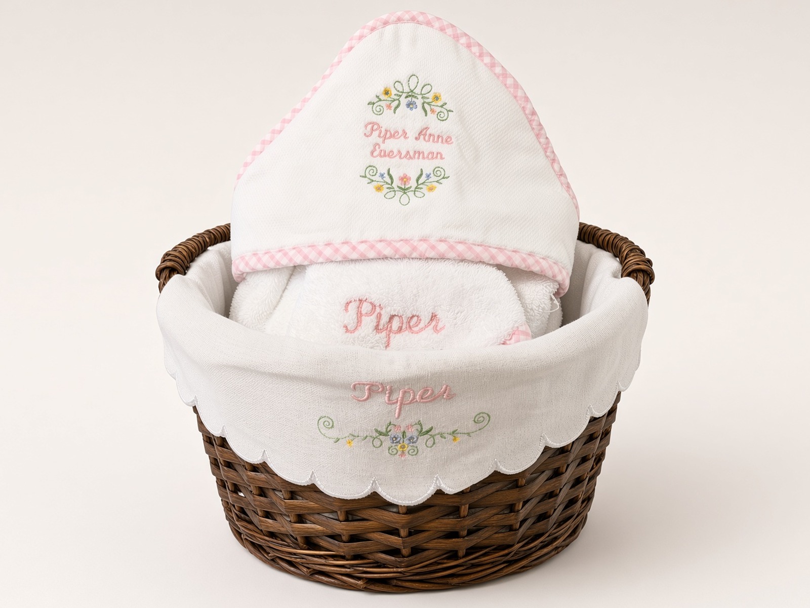 Wicker gift basket with a hooded baby towel and linens embroidered Piper Anne Eversman